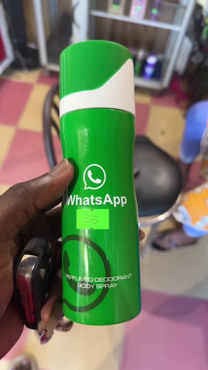 A hand holding a green WhatsApp-branded perfumed deodorant body spray in a shop, price sticker 35